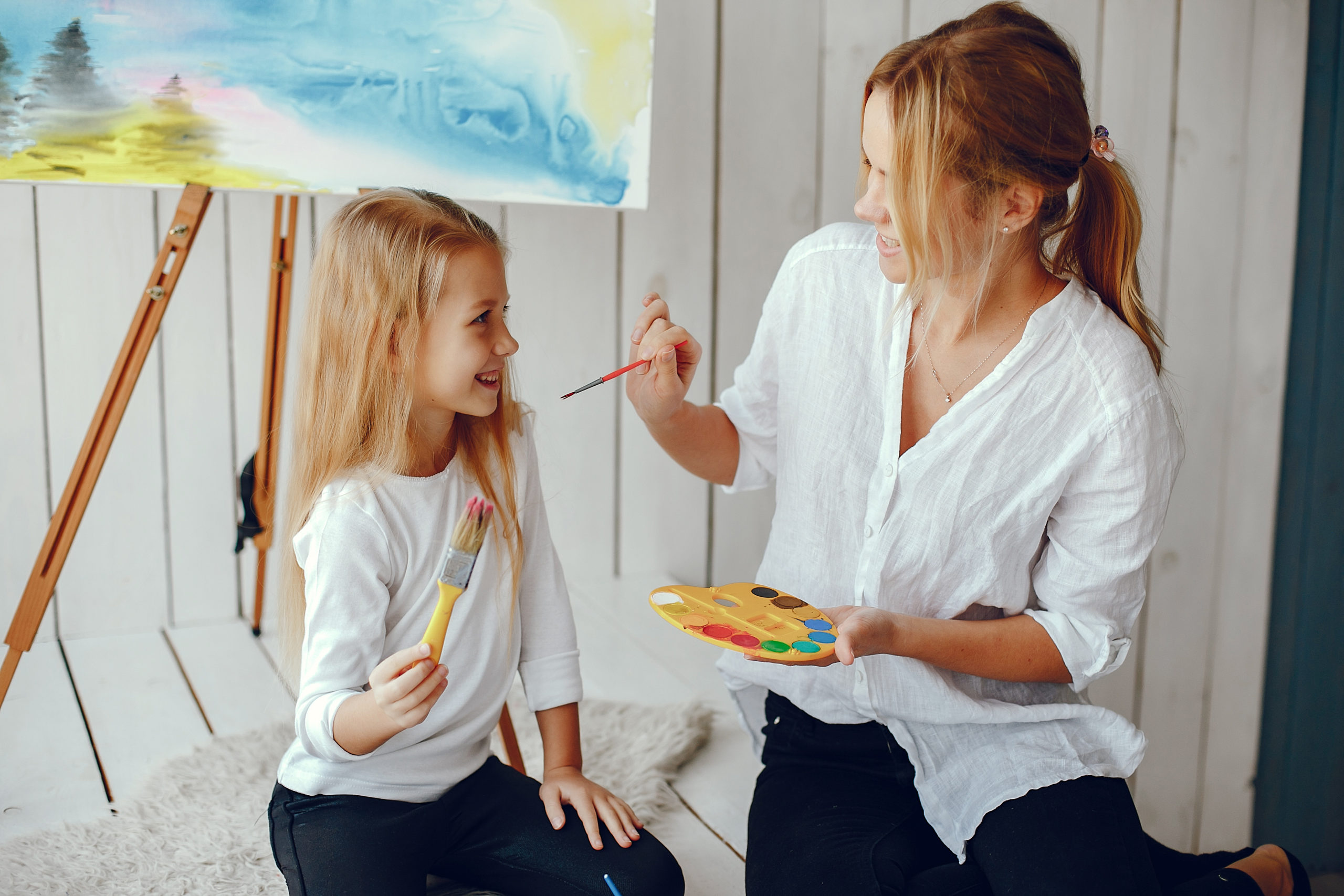 Beautiful little girl painting. Mother drawing with little girl.